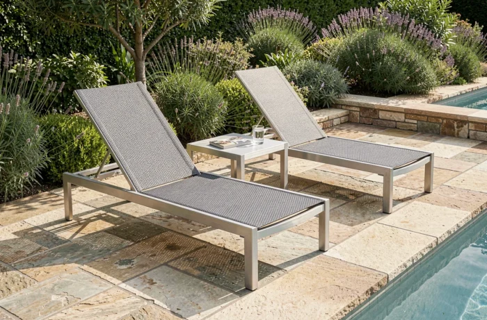 Bain de soleil en aluminium et textilène gris au bord d'une piscine de jardin