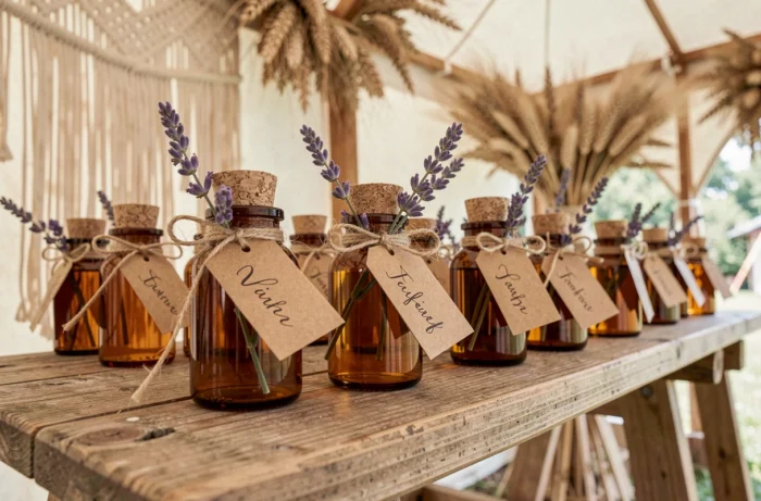 Cadeaux d'invités de mariage artisanaux en petites bouteilles de miel avec étiquettes calligraphiées et lavande séchée