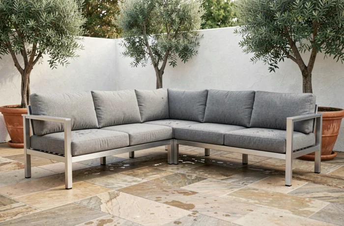 Salon d'angle en aluminium avec coussins déperlants gris sur une terrasse en pierre